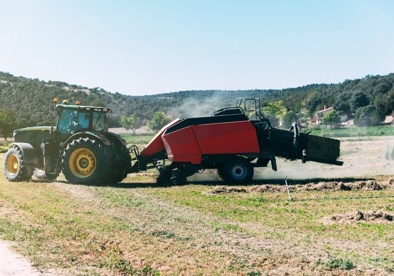 Tracteur tirant une presse à balles dans un champ