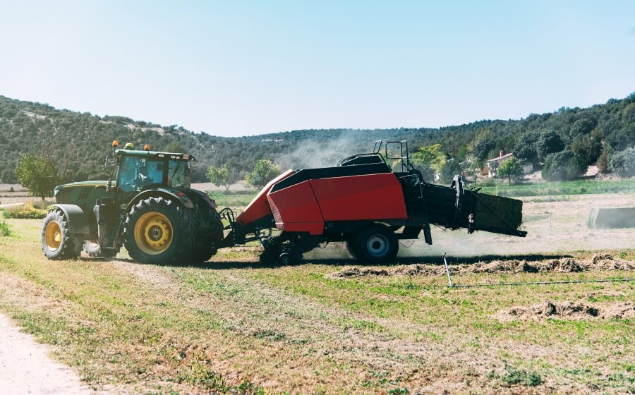 Tracteur tirant une presse à balles dans un champ